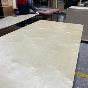 Factory workers handling a large premium veneer plywood panel at SunShine NHN facility.